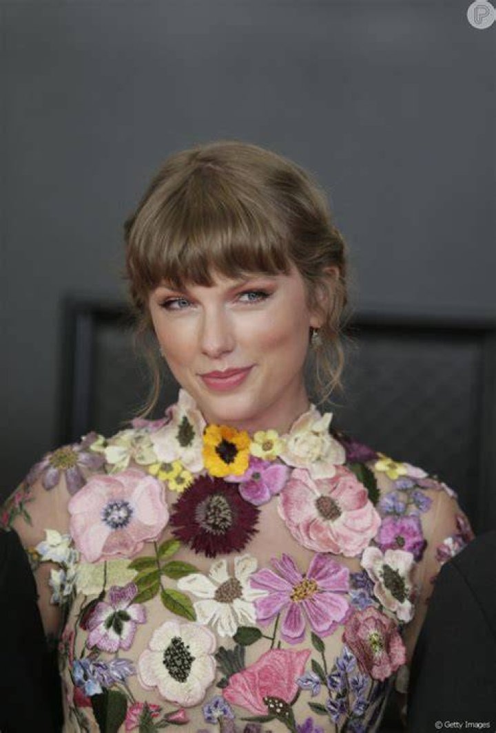 Taylow Swift aposto em penteado preso com fios desconectados e